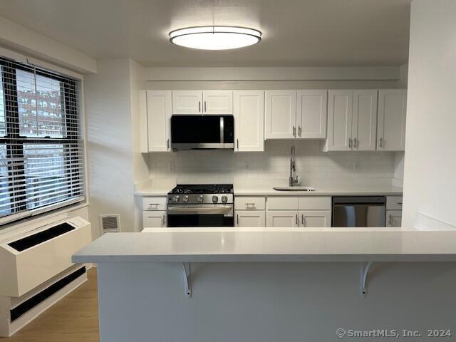 a kitchen with stainless steel appliances a stove a microwave and white cabinets