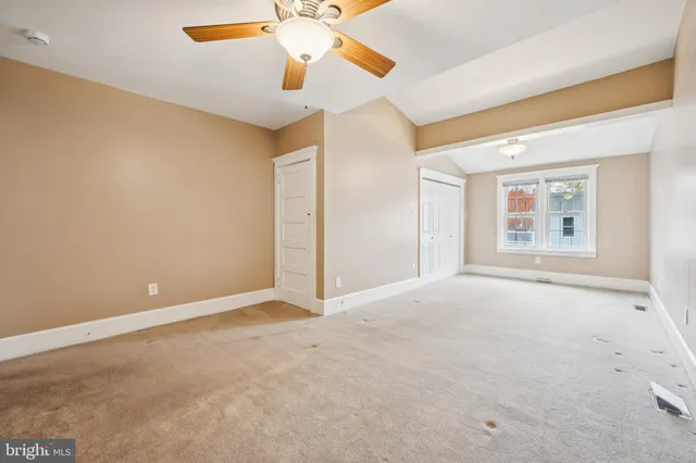 an empty room with a chandelier fan and windows