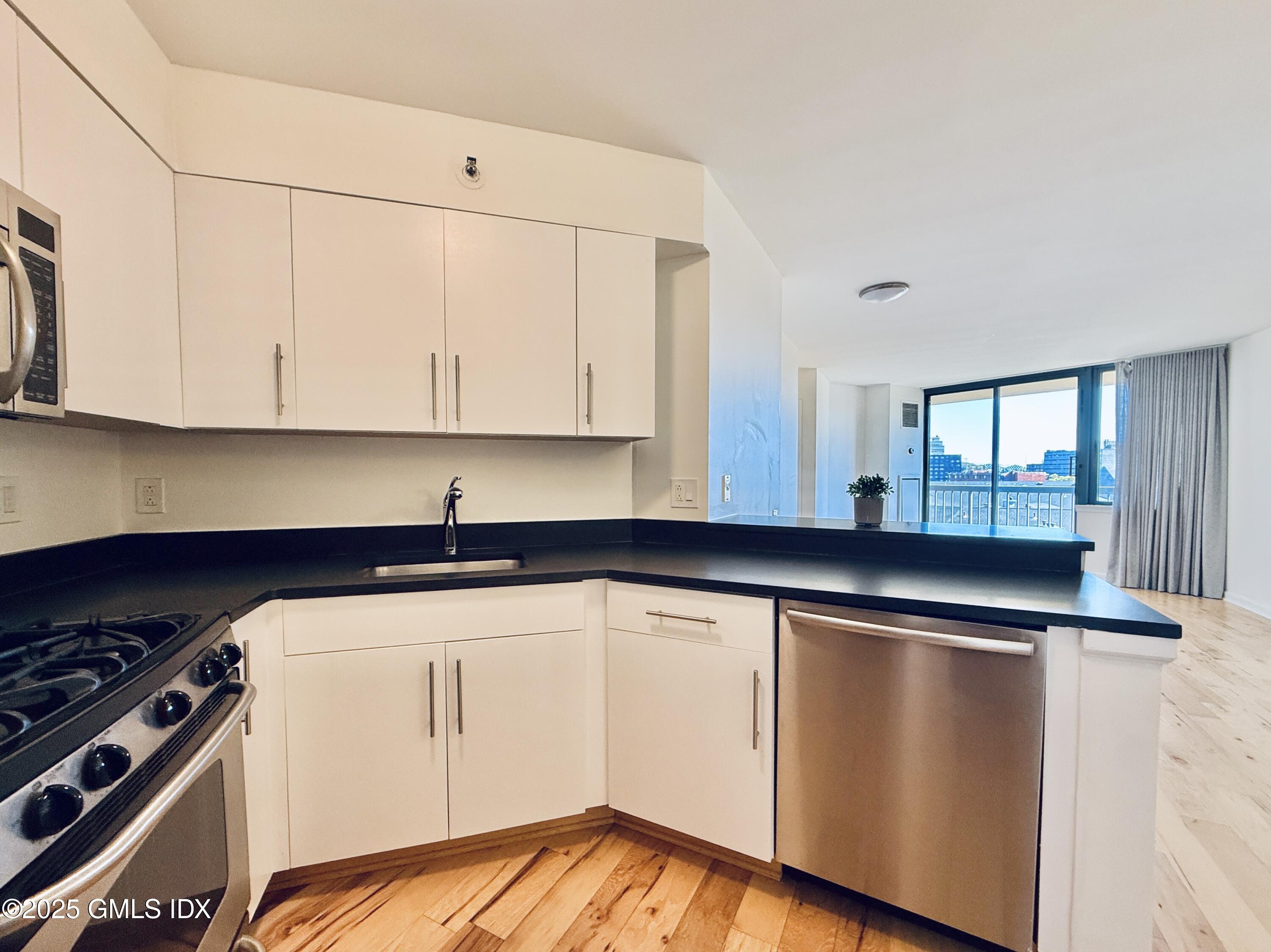 25 Forest Street, Unit 8C Stamford, CT 06901 - Photo 6 of 25 a kitchen with granite countertop a stove and white cabinets