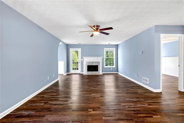 an empty room with fireplace chandelier fan and windows