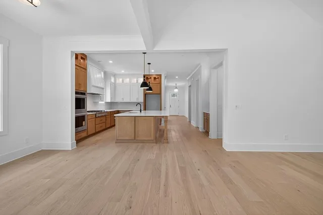 a large kitchen with a wooden floor and stainless steel appliances