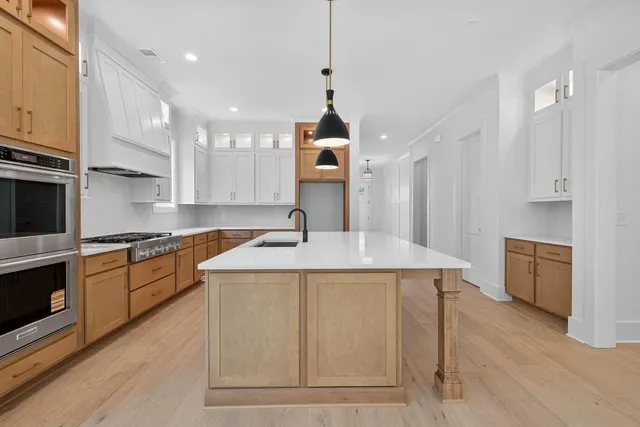 a kitchen with kitchen island a stove a sink a center island and wooden floor