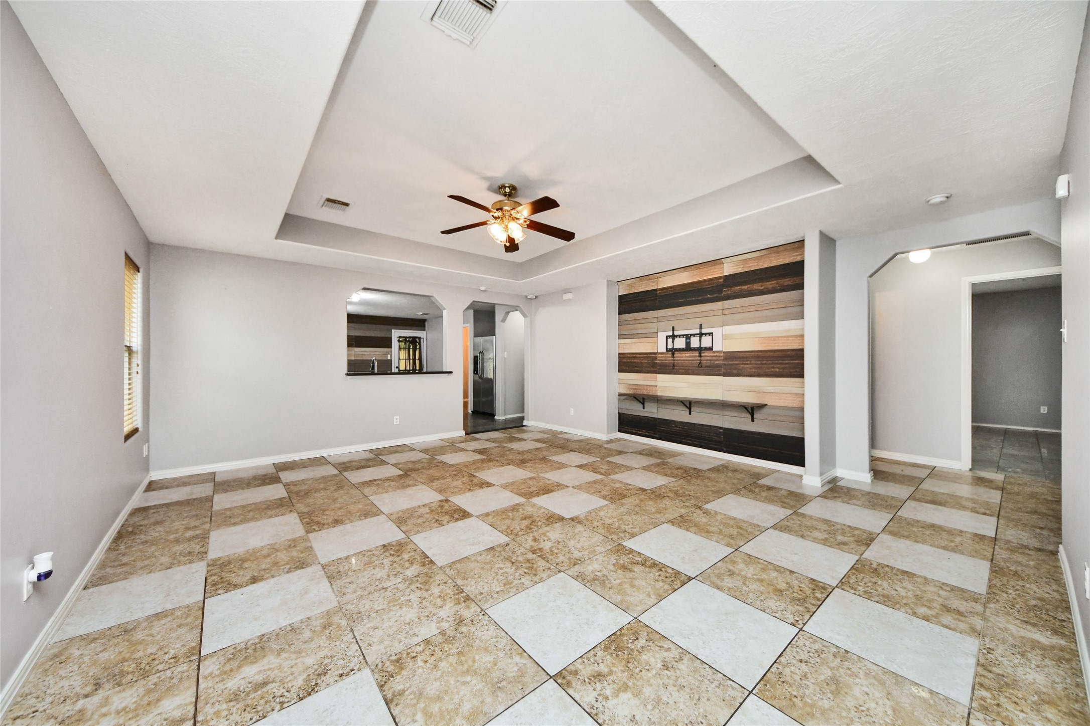 24019 Kingbriar Drive Spring, TX 77373 - Photo 9 of 41 The spacious living area is highlighted by a tray ceiling with a cooling ceiling fan and a unique wood-plank accent wall, creating a beautiful focal point for the home.