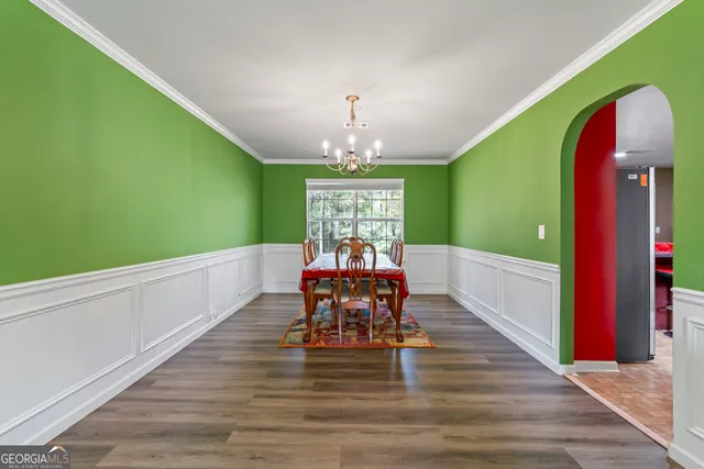 a view of a kitchen with kitchen island stainless steel appliances a stove a refrigerator a sink dishwasher and a dining table with wooden floor