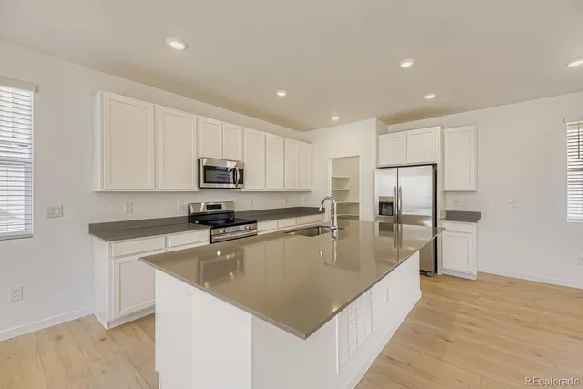 a large kitchen with stainless steel appliances granite countertop a lot of counter space and wooden floors