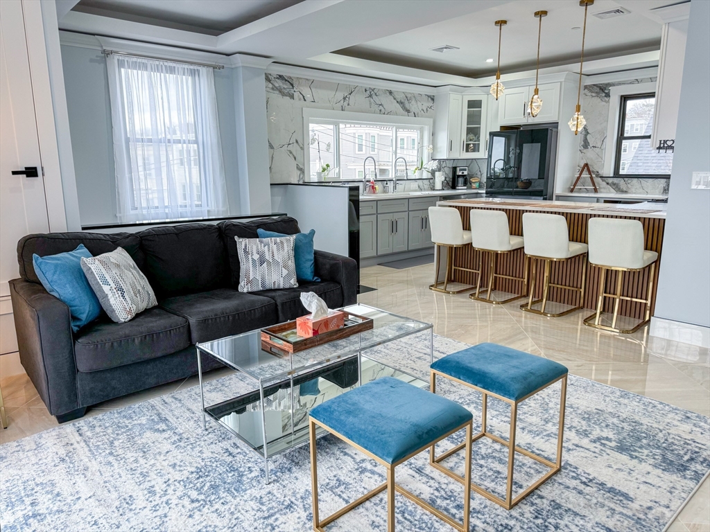 a living room with furniture wooden floor and kitchen view