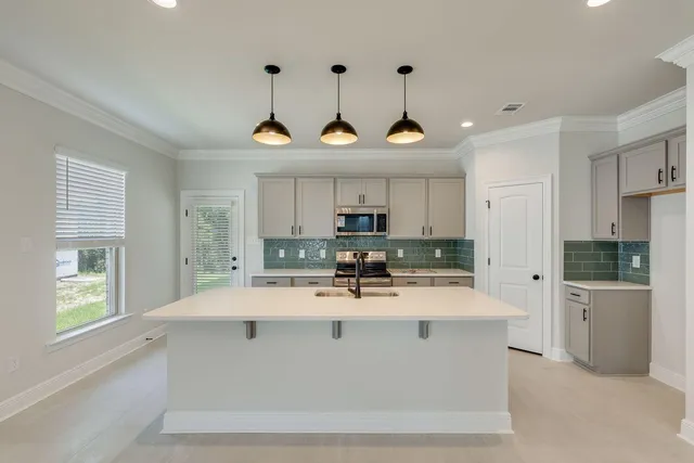 a kitchen with granite countertop a sink a counter top space stainless steel appliances and cabinets