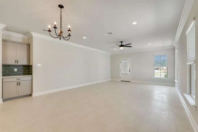 an empty room with chandelier and stainless steel appliances