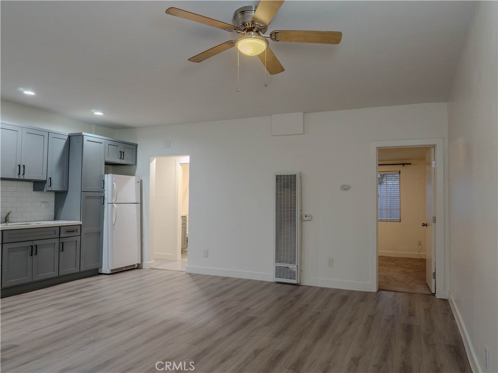 9413 Garfield Street Riverside, CA 92503 - Photo 3 of 19 a view of a kitchen with a refrigerator a ceiling fan and wooden floor
