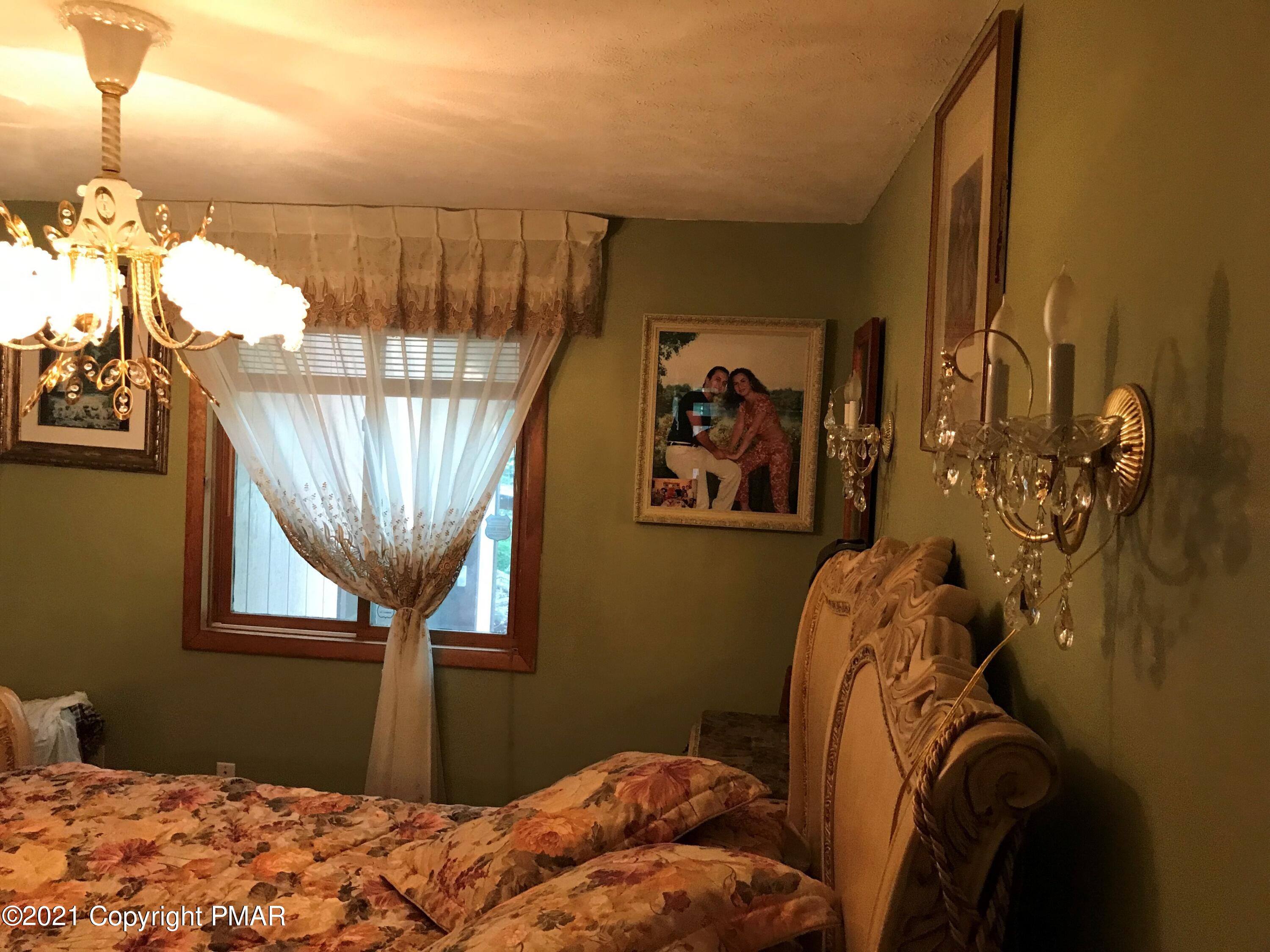 716 Dundee Road Bushkill, PA 18324 - Photo 16 of 38 a bedroom with a bed and a chandelier