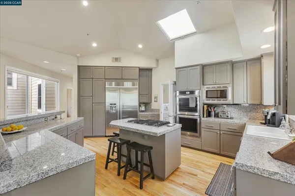 a kitchen with granite countertop kitchen island stainless steel appliances a sink stove and refrigerator