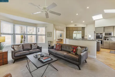 a living room with furniture and a large window with kitchen view