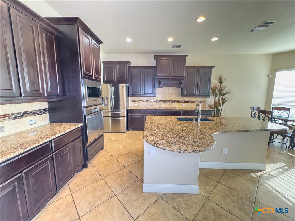 809 Alpino Cibolo, TX 78108 - Photo 14 of 29 a large kitchen with kitchen island granite countertop wooden cabinets a granite counter and a sink