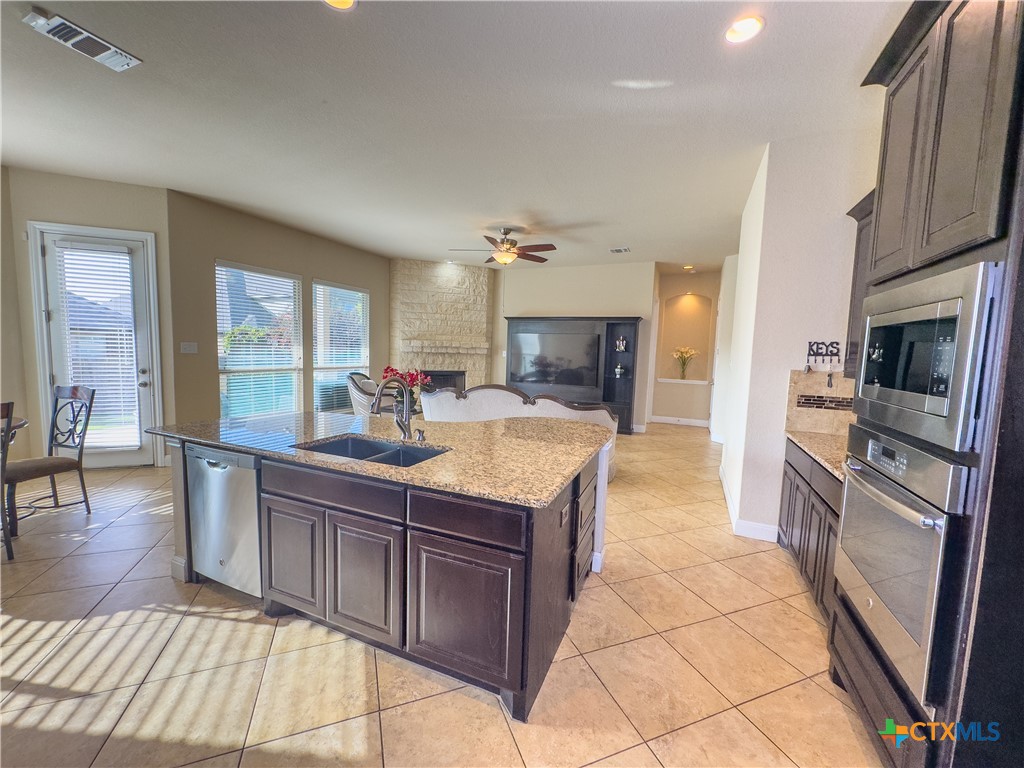 809 Alpino Cibolo, TX 78108 - Photo 10 of 29 a kitchen with stainless steel appliances granite countertop a stove top oven a sink dishwasher a dining table and chairs with wooden floor