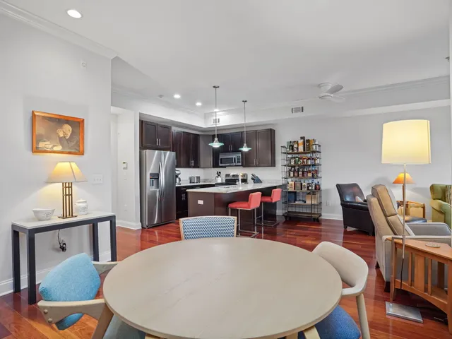 a kitchen with stainless steel appliances kitchen island granite countertop a dining table chairs and a refrigerator
