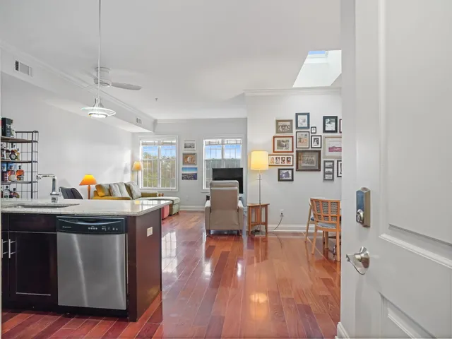 a living room with stainless steel appliances furniture and a wooden floor