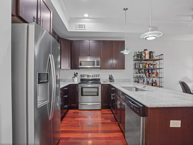 a kitchen with stainless steel appliances granite countertop a refrigerator a stove and a sink