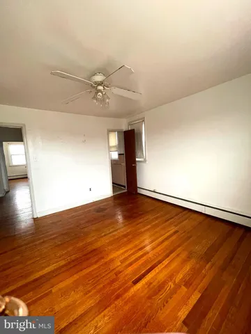 an empty room with wooden floor and fan