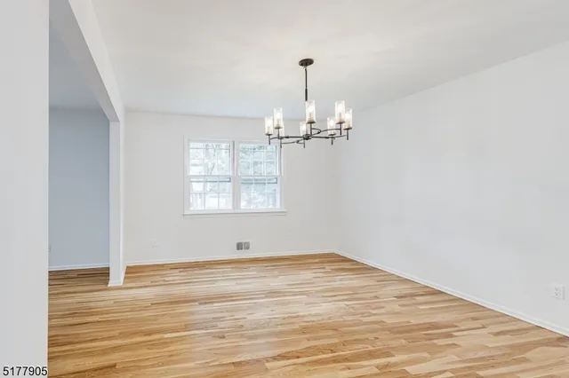 a view of empty room with wooden floor fan and window