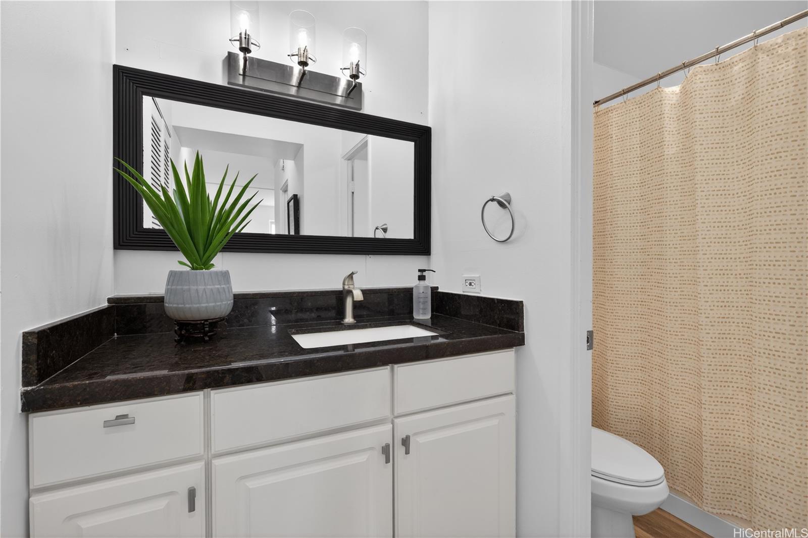 98-1038 Moanalua Road, Unit 7608 Aiea, HI 96701 - Photo 12 of 25 a bathroom with a granite countertop sink a toilet and a mirror