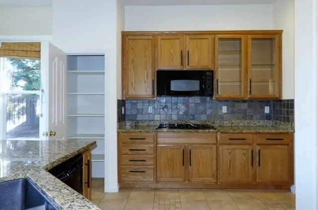 a kitchen with granite countertop a stove top oven microwave and cabinets