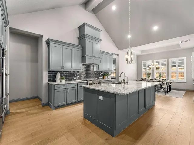 a kitchen with kitchen island granite countertop a sink stove and cabinets