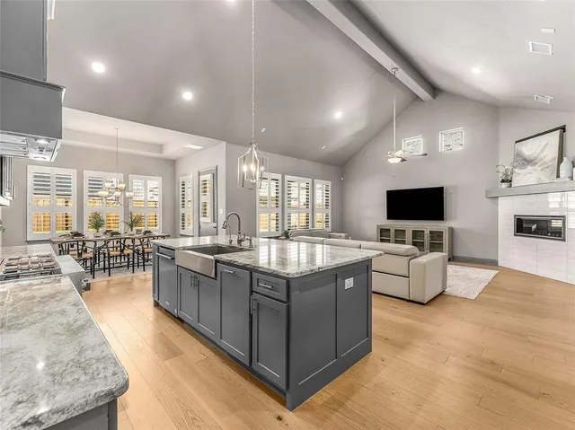 a large living room with stainless steel appliances granite countertop couches a flat screen tv and a large window