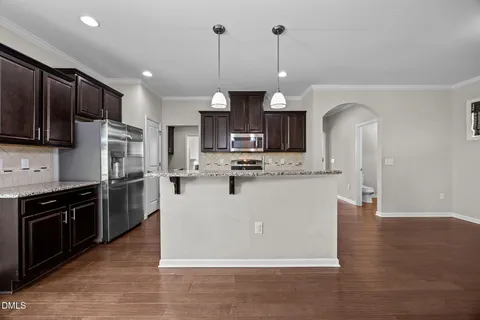 a kitchen with kitchen island granite countertop stainless steel appliances and wooden cabinets