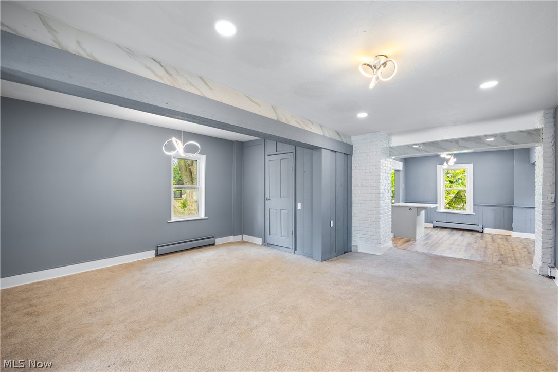 39016 Detroit Road Avon, OH 44011 - Photo 6 of 36 Unfurnished living room with a baseboard radiator, a wealth of natural light, light carpet, and brick wall
