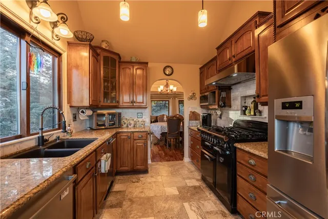 a kitchen with stainless steel appliances granite countertop a sink a stove and a refrigerator