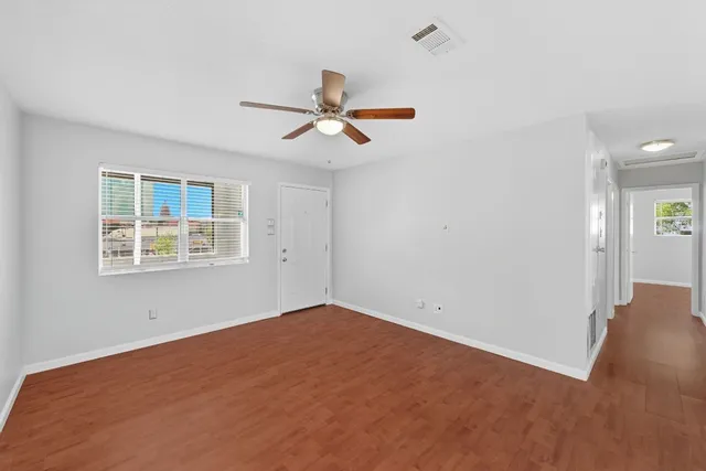 a view of a room with wooden floor and a ceiling fan