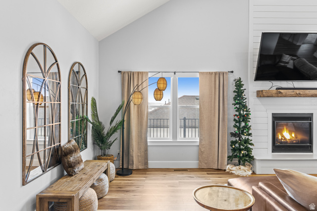 1343 North Trapper Loop Garden City, UT 84028 - Photo 13 of 56 Living area featuring light wood-style floors, vaulted ceiling, and a glass covered fireplace