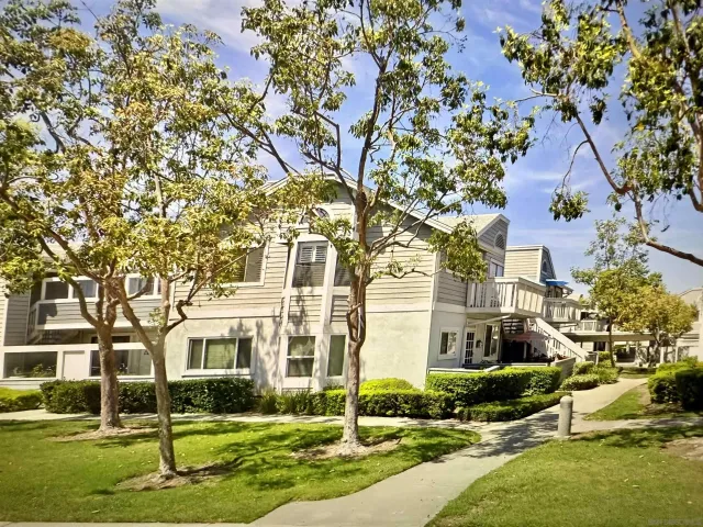 a view of a white house next to a yard with big trees