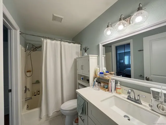 a bathroom with a sink a toilet a large mirror and shower