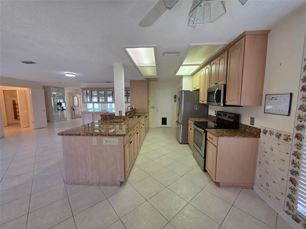 2376 Bent Pine Court Spring Hill, FL 34606 - Photo 8 of 33 a kitchen with stainless steel appliances kitchen island granite countertop a refrigerator a stove a sink and dishwasher