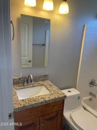 a bathroom with a granite countertop sink and a toilet