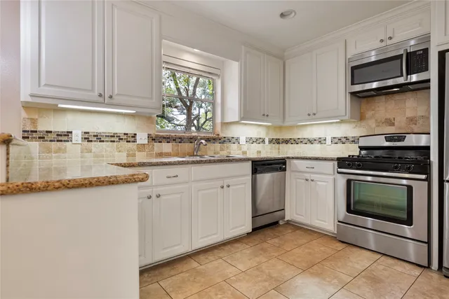 a kitchen with granite countertop a sink stainless steel appliances and cabinets