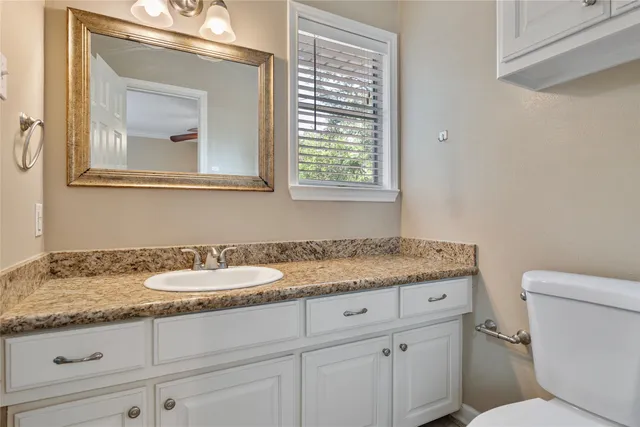 a bathroom with a granite countertop toilet sink and mirror