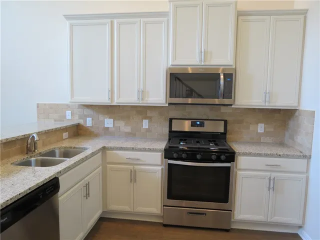 a kitchen with granite countertop white cabinets and stainless steel appliances