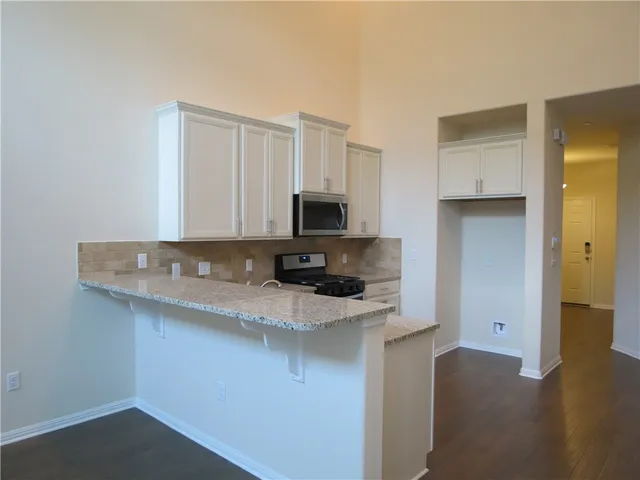 a kitchen with stainless steel appliances granite countertop a sink a stove and a refrigerator