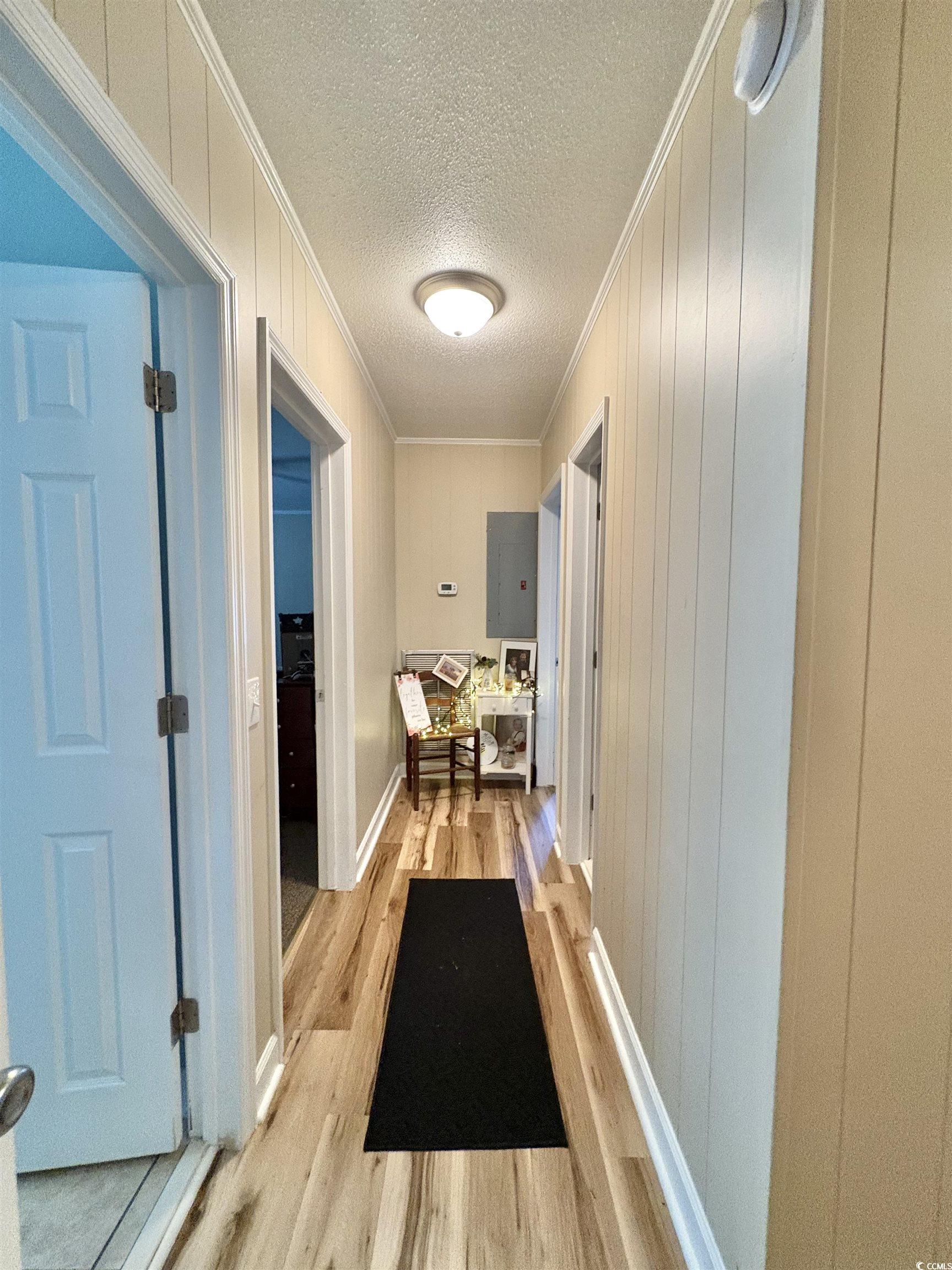 520-526 Boundary Avenue Murrells Inlet, SC 29576 - Photo 8 of 38 Hallway with crown molding, light wood-type flooring, wood walls, and a textured ceiling