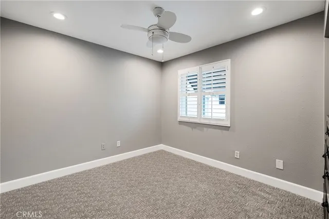 en empty room with windows and ceiling fan