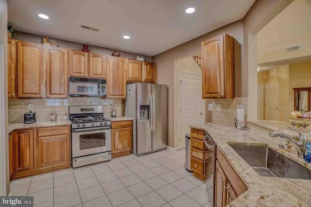 a kitchen with kitchen island granite countertop a stove sink microwave and refrigerator