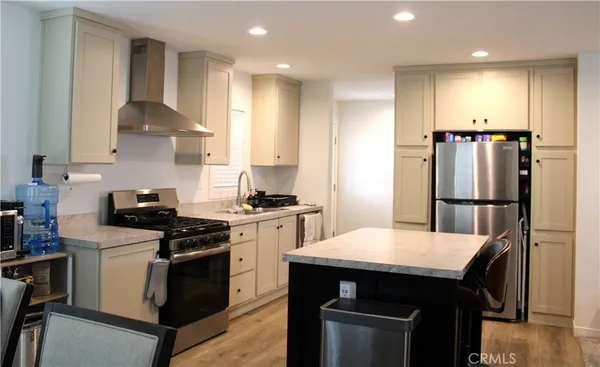 a kitchen with stainless steel appliances granite countertop a stove a refrigerator a sink a dining table and chairs
