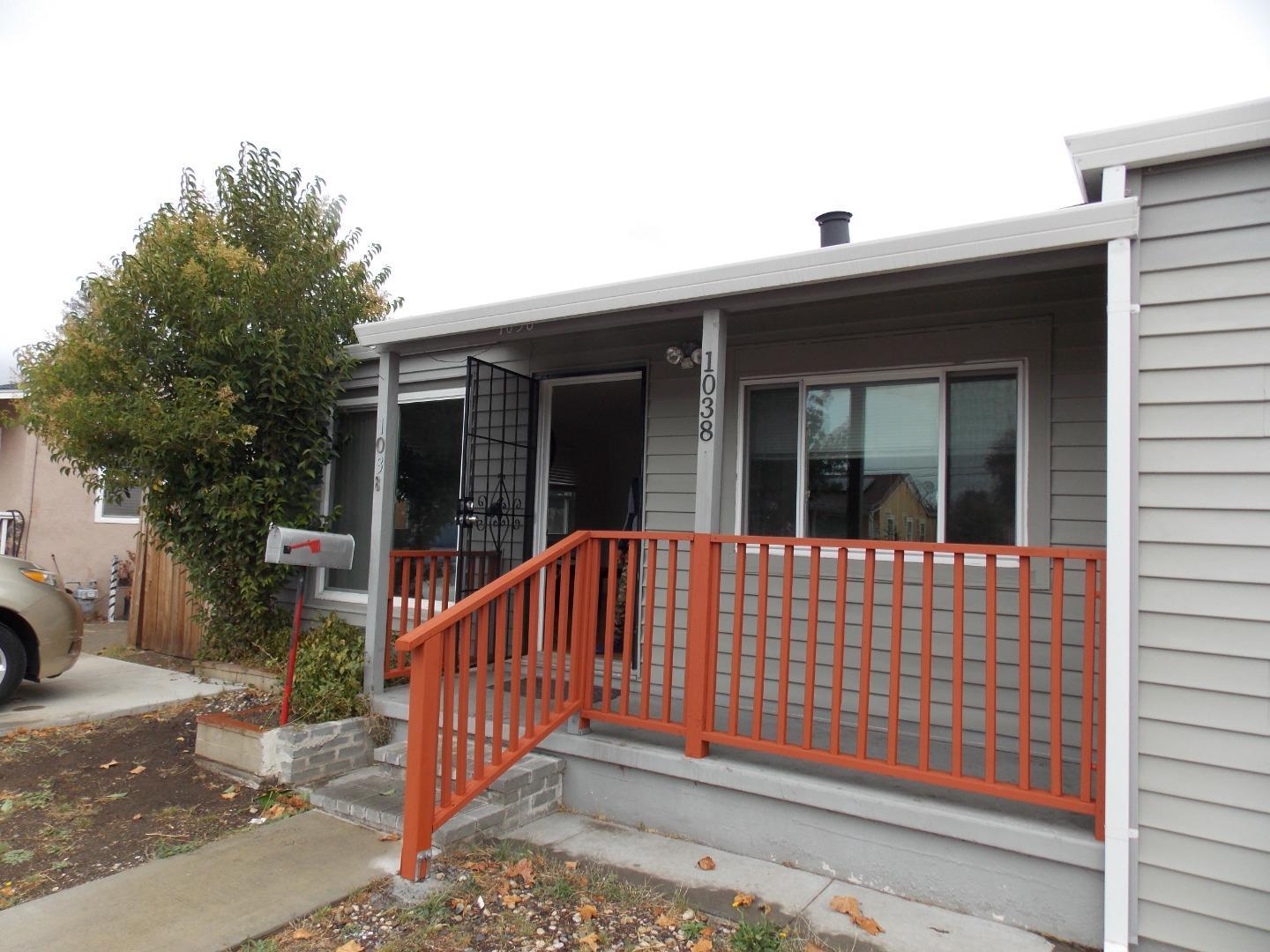 a view of a brick house with large windows and wooden fence