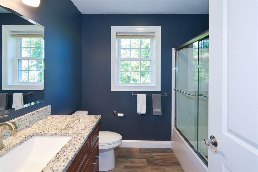 310 Main Street Rutland, MA 01543 - Photo 28 of 39 a bath room with a granite countertop toilet a sink a mirror and a window