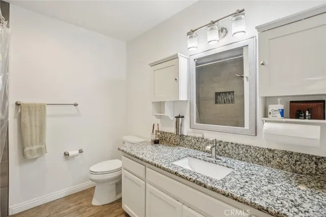 a bathroom with a granite countertop sink toilet and mirror
