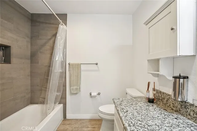 a bathroom with a granite countertop sink a toilet and shower