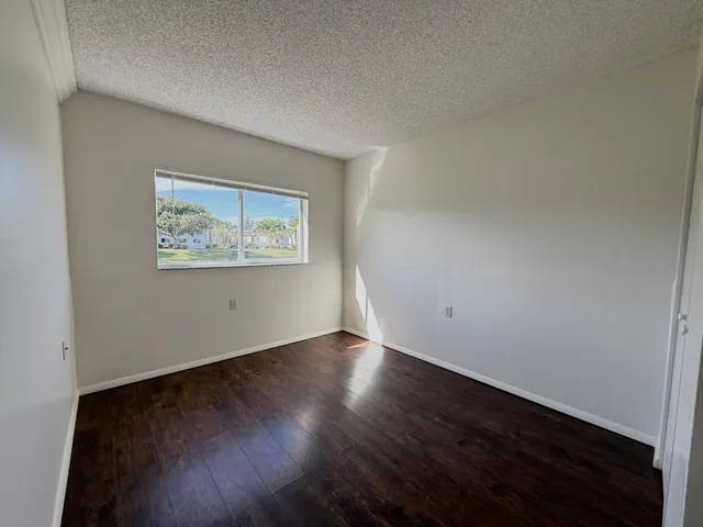 an empty room with wooden floor and window