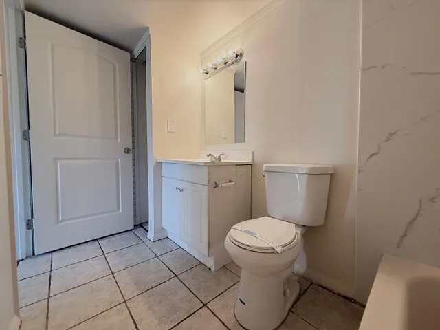 a bathroom with a granite countertop toilet and a sink
